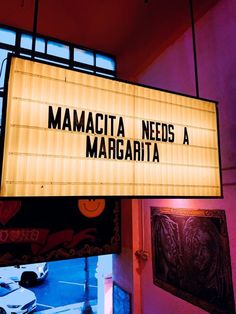 a sign hanging from the side of a building that says mamacit needs a margarita