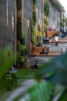 people are sitting on the steps in front of a building with plants growing all over it