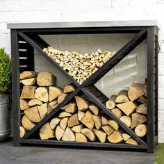 a stack of firewood sitting in front of a white brick wall