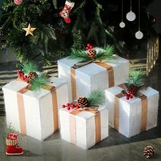 four wrapped presents sitting next to a christmas tree