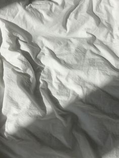 an unmade bed with white sheets and pillows