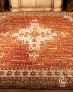 an orange and beige area rug in front of a window