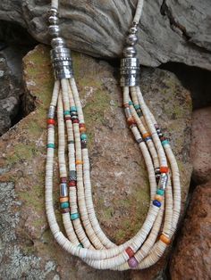 This is a beautiful Handcrafted Native American Made Multi strand Heishi necklace. Each necklace is entirely Handcrafted which makes it a ONE OF A KIND you get the exact necklace shown in the pictures. The necklaces that I sell are meticulously crafted by Native American bead workers, and the quality and attention to detail is truly exceptional. The necklace measures about 30" (end to end) bead length is 27" it has a Sterling Silver toggle clasp closer.  It has five wonderful strands that have a beautiful mix of colors.   With all the colorful gemstones it will be sure to match almost any outfit.  The Multi Colored mix of Gemstones and the hand stamped Sterling Silver beads add a very rich look to this work of art. I personal own one of these and it is my favorite necklace the colors are s Bohemian Single Strand Round Jewelry, Artisan Multicolor Single Strand Necklace, Artisan Lariat Jewelry With Colorful Beads, Handmade Southwestern Long Necklace, Artisan Lariat Necklace With Colorful Beads, Artisan Long White Necklace, Artisan Jewelry With Colorful Beads In Lariat Style, Artisan Jewelry With Colorful Beads In Lariat Shape, Artisan White Long Necklace