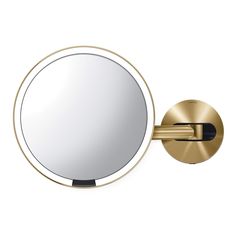 a round mirror mounted on the wall next to a gold faucet with a black handle