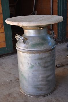 a metal container with a wooden lid sitting on the floor next to a fire place