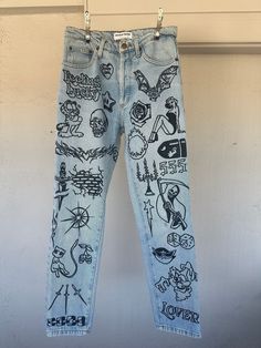 a pair of jeans with drawings on them hanging from a clothes line