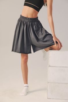 a woman in black top and grey skirt posing