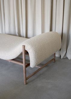 a white bench sitting on top of a cement floor next to a curtained window