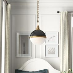 a white bed sitting under a hanging light in a bedroom