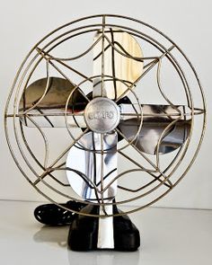 a metal fan sitting on top of a white table next to a black and silver object