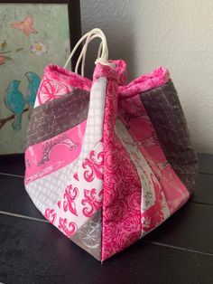 a pink and gray bag sitting on top of a table next to a framed painting