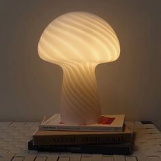 a mushroom lamp sitting on top of two books next to a white wall and floor