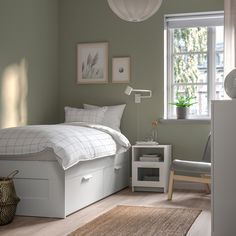 a bed room with a neatly made bed next to a window and a rug on the floor