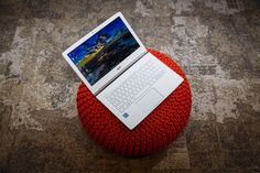 an open laptop computer sitting on top of a red ottoman