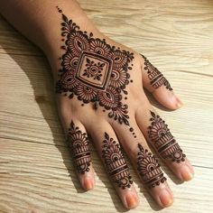 a henna tattoo on someone's hand that is sitting on a wooden table