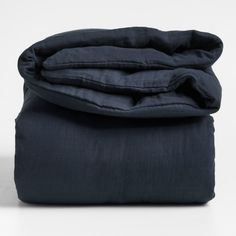 an unmade bed with dark blue sheets and pillows on the bottom, in front of a white background