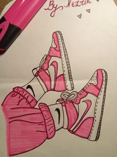 a drawing of a pair of pink shoes on top of a piece of paper next to a marker