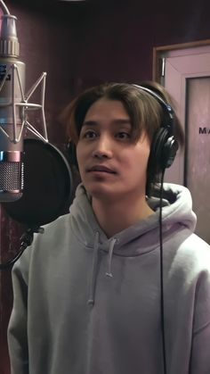 a young man wearing headphones standing in front of a microphone