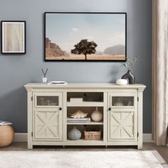 a living room with blue walls and a white entertainment center in front of a painting on the wall