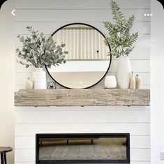 there is a mirror on top of the fireplace mantel with plants and vases