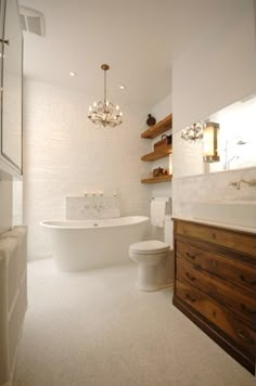 a bathroom with a tub, toilet and chandelier hanging from it's ceiling