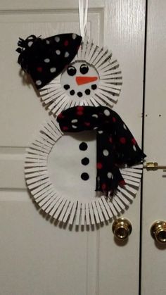 a paper plate snowman hanging on the front door with black and white polka dots