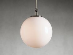 a white light hanging from a ceiling fixture in a room with gray walls and flooring