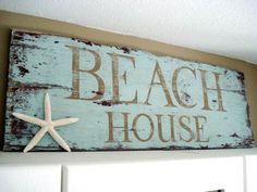 a wooden sign that says beach house on top of a shelf next to a starfish