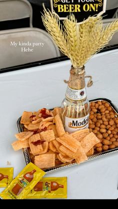 a bottle of beer sitting on top of a tray filled with food next to snacks