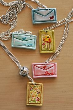 four necklaces with different designs on them sitting on a wooden table next to each other