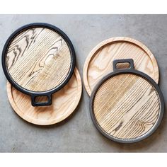 two wooden coasters sitting on top of a cement floor next to each other with black handles