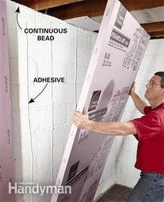 a man holding up a large box in the middle of a room with exposed walls