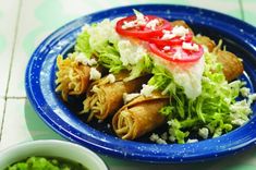 a blue plate topped with tacos covered in lettuce and tomatoes