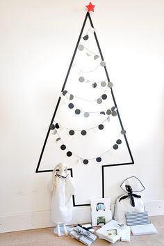 a white christmas tree sitting on top of a wooden floor next to a wall with black dots