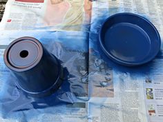 a blue pot sitting on top of a newspaper next to a plastic cup and saucer