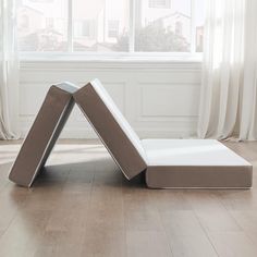 a white couch sitting on top of a hard wood floor next to a large window