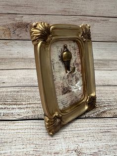 an ornate gold frame with a glass doorknob in the center on a wooden surface