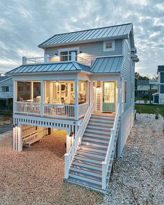 a white house with stairs leading up to the front door and second story on stilts