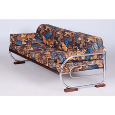 a blue and orange couch sitting on top of a metal frame with wooden feetrests