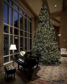 a living room with a christmas tree and piano