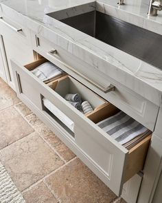 an open drawer in the middle of a kitchen counter with towels and napkins inside