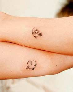 two women with matching tattoos on their arms, one has a flower and the other has an arrow