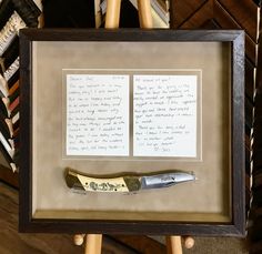 a pair of scissors sitting on top of a wooden frame next to a piece of paper