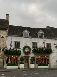 a white building with flowers and wreaths on the front windows is next to a street