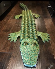 an alligator made out of paper sitting on top of a wooden floor