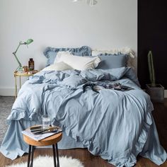 a bed with blue sheets and pillows in a bedroom next to a white rug on the floor