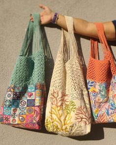 three purses are lined up on the ground with one being held by someone's arm