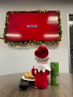 a elf sitting at a table in front of a red screen with the word netflix on it