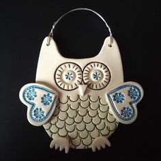 an owl ornament hanging on a black background with blue and green accents in the shape of a purse