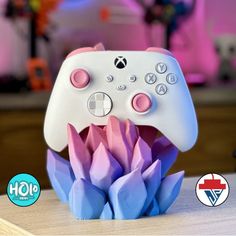 a video game controller sitting on top of a wooden table next to a purple flower